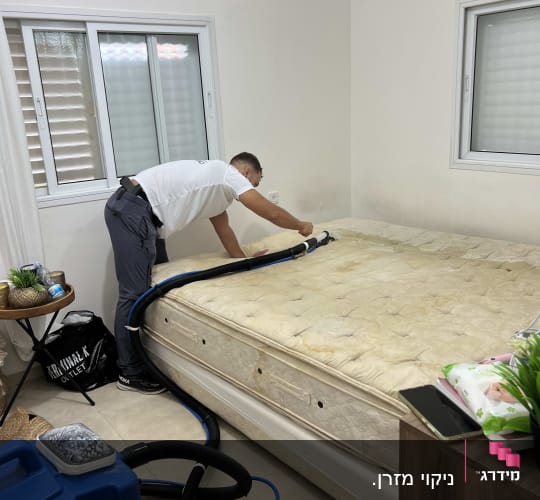 אדם מנקה מזרן עם מכונת ניקוי כחולה